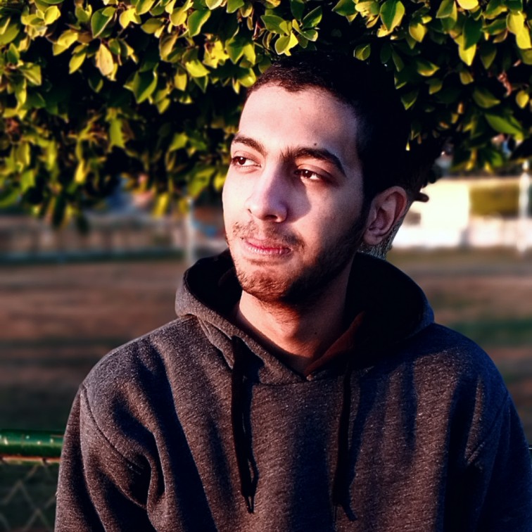 mustafa dabah smiling in a gray shirt and tortoise shell